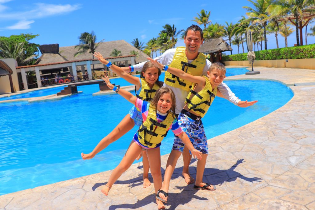 Family in life vests smiling by the dolphin pool