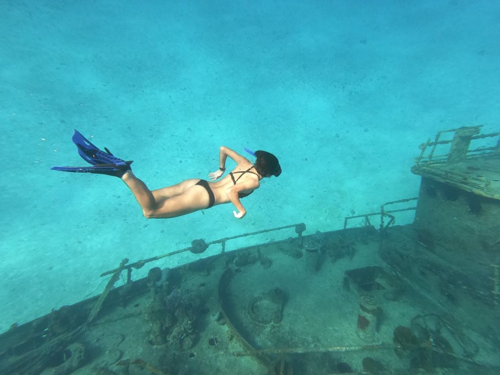 Snorkeler swimming over a shipwreck in the clear water of Cozumel